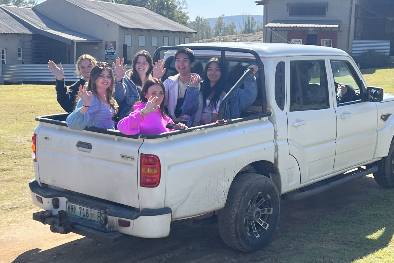 Students wave from the bed of a truck in South Africa